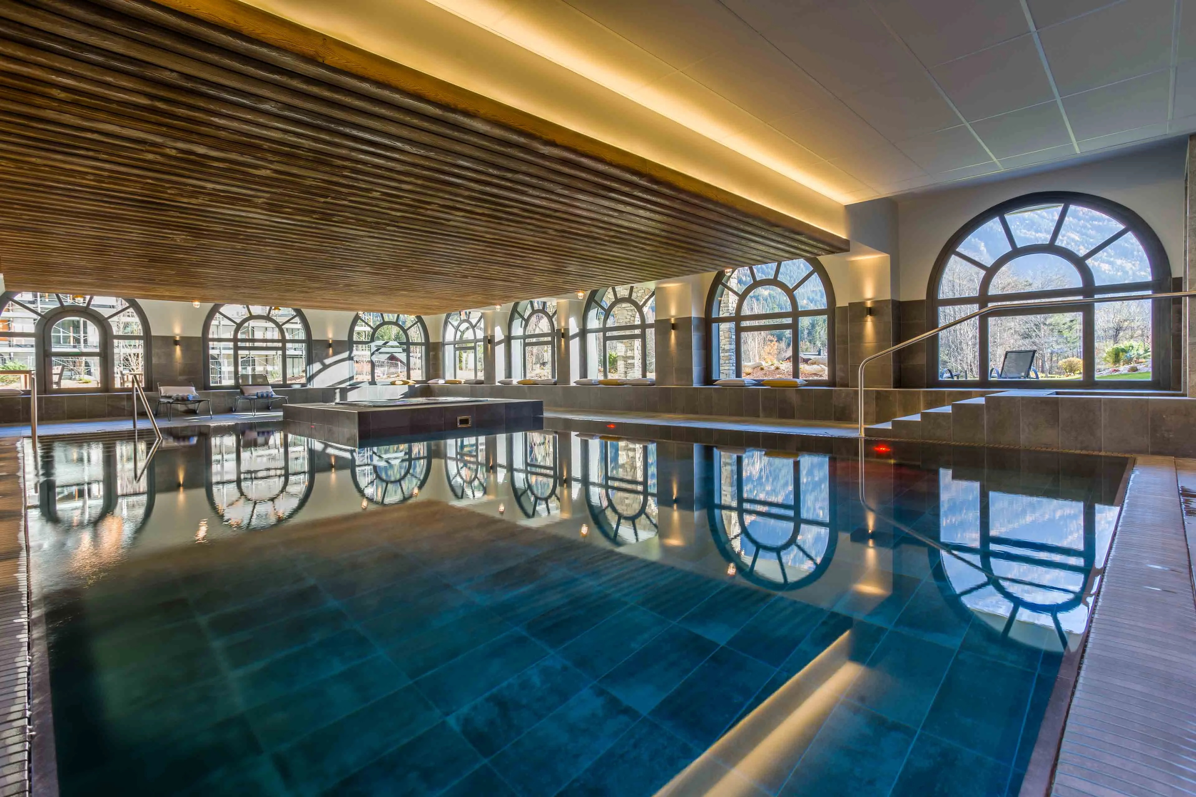Piscine intérieure avec baies vitrées cintrées donnant sur les montagnes à Chamonix